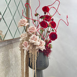 Decorative vase with red and pink flowers on a tiled surface