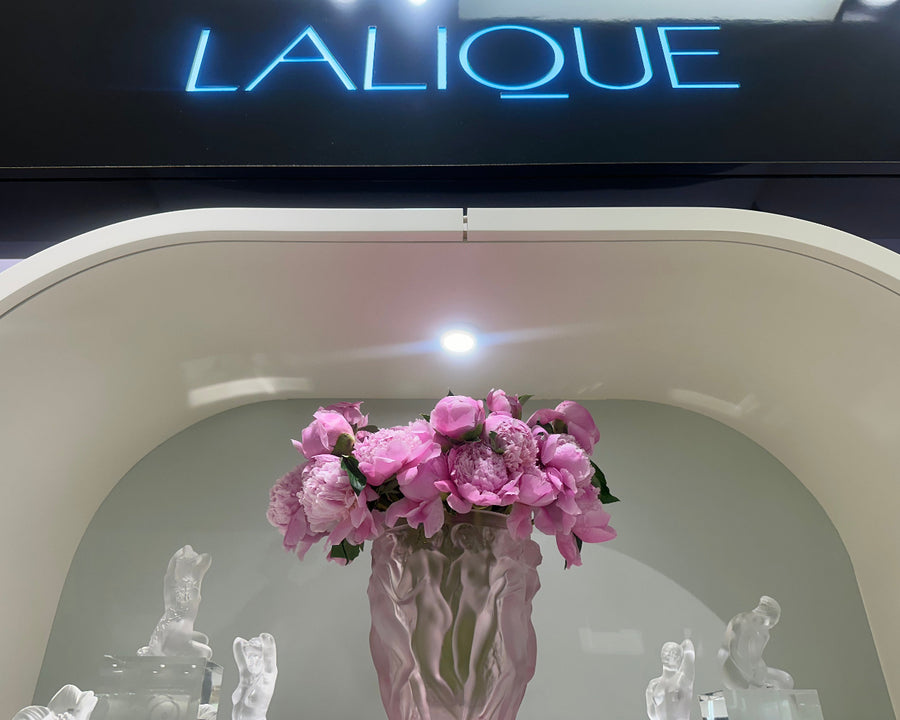 Pink vase with flowers in front of a Lalique sign floral design by AY Flowers
